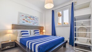 Une chambre moderne avec un lit, des lampes de chevet, une fenêtre avec des rideaux, une étagère fixée au mur et une fresque murale représentant des poissons aux couleurs vives.