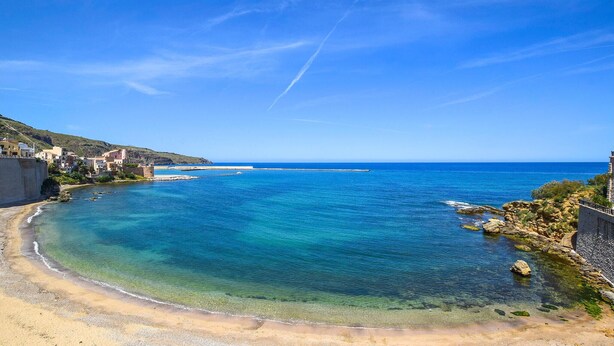 Une ville côtière aux eaux d’un bleu limpide, aux plages de sable fin et aux bâtiments qui bordent le rivage.
