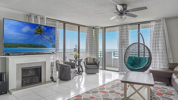 A spacious living room with a large flat-screen TV, a fireplace, comfortable seating, and a balcony with a view of the ocean. - 2/2 OCEANFRONT 8th Floor Unit with Open Pool (Daytona Beach)