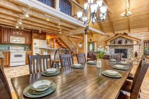 A spacious wooden dining area with a long table set for a meal, surrounded by wooden chairs. - Running Bears Den- Chalet Village’s Perfect Retreat in the Mountains (Gatlinburg)