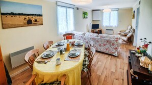 Un coin repas avec une table dressée pour quatre personnes, un canapé et un téléviseur en arrière-plan.