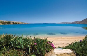 A serene beach with clear blue waters, a sandy shore, and lush greenery in the foreground. - 4 bedroom amazing home in Povljana (Povljana)