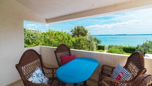 A balcony with wicker chairs and a small table, overlooking a scenic view of a body of water and greenery. - 4 bedroom amazing home in Povljana (Povljana)