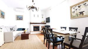 A modern living room with a fireplace, a dining area with a table and chairs, and a sofa. - 4 bedroom amazing home in Povljana (Povljana)