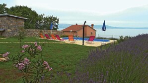 A house with a swimming pool, surrounded by a garden with lavender and pink flowers.