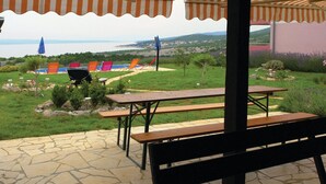 A patio with stone flooring, picnic tables, and colorful chairs.