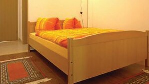 A single bed with a wooden frame and a yellow blanket.