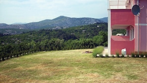 A red building with a balcony overlooking a vineyard and mountains.
