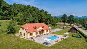Una casa con piscina, rodeada de un paisaje verde exuberante y montañas al fondo.