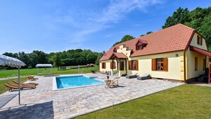Una casa con piscina, mobiliario de exterior y jardín.