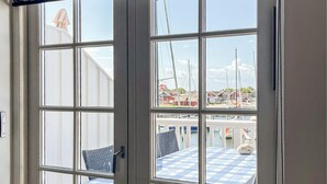 Blick durch ein Fenster auf einen Tisch und Stühle mit karierter Decke draußen.