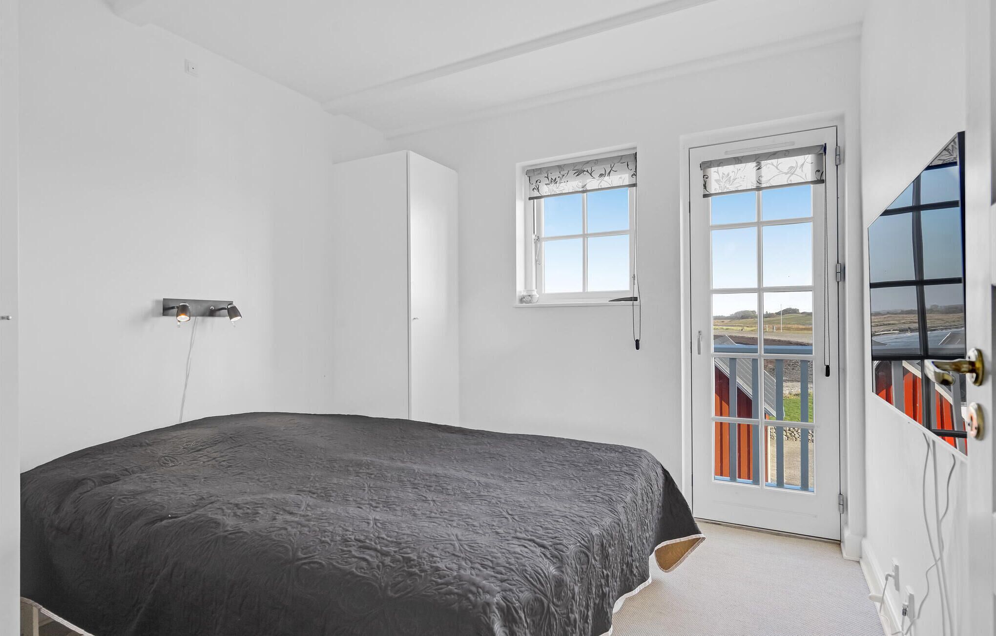 Un dormitorio con cama, ventana y puerta que da al exterior.