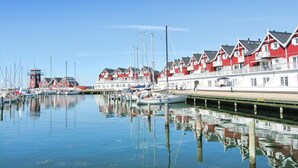 Ein Yachthafen mit roten und weißen Gebäuden, ruhigem Wasser und vertäuten Booten.