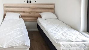 A room with two single beds, each with white bedding and a wooden headboard.
