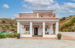A two-story house with a balcony, a tiled roof, and a gravel driveway. - Awesome home in Malaga (Malaga)
