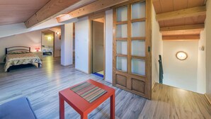 Ruime loft slaapkamer met houten plafond, een grote schuifpui en een bed met een bloemenprint deken.