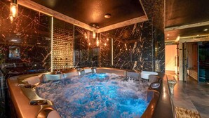 Ein Whirlpool mit Marmorinnenraum, umgeben von Holzverkleidungen und einer Glastrennwand.