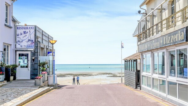 Eine Küstenstraße mit einem Restaurant namens 'Restaurant de la Mer' und einer Pizzeria.
