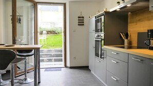 Eine moderne Küche mit grauen Schränken, Edelstahlgeräten und einer Holz Arbeitsplatte.