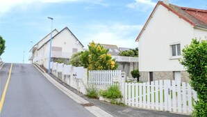 Eine Wohnstraße mit Häusern, einem weißen Zaun und blauem Himmel.