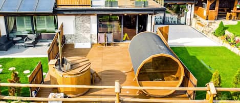A modern outdoor deck with a wooden barrel, a large cylindrical structure, and a wooden fence.