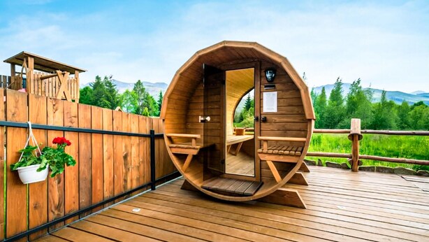 Una struttura a forma di cupola in legno con una porta, un tavolino e una panca all'interno.