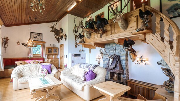 A rustic interior with a wooden staircase, a fireplace, and various animal heads mounted on the walls. - Ferienhaus - St. Koloman (St. Koloman)