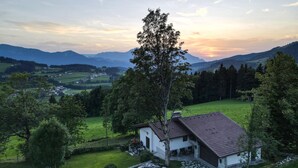 A rural house with a stone pathway leading to the entrance, surrounded by lush greenery and a mountainous backdrop. - Ferienhaus - St. Koloman (St. Koloman)