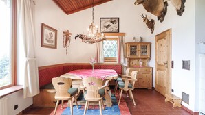 A dining area with a wooden table, chairs, and a chandelier. - Ferienhaus - St. Koloman (St. Koloman)