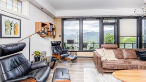 A modern living room with leather furniture, a bookshelf, a large window with a view of mountains, and a dining area. - Gorgeous home in Vestnes with WiFi (Vestnes)