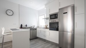 Ett modernt kök med inbyggd diskmaskin, ett kylskåp i rostfritt stål och en mikrovågsugn.