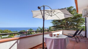 Uma varanda com mesa, cadeiras e um grande guarda-sol.
