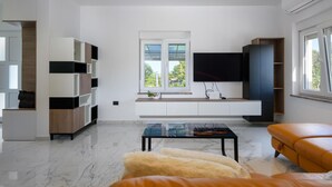 Una sala moderna con un ventanal grande, un televisor de pantalla plana y un sofá.