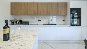 Una cocina moderna con armarios de madera, horno empotrado y encimera de mármol.