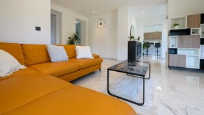 Una sala moderna con un sofá, una mesa de centro y una cocina al fondo.