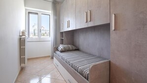Ein gemütliches Schlafzimmer mit integriertem Bett, Heizkörper und Fenster mit Blick auf die Stadt.