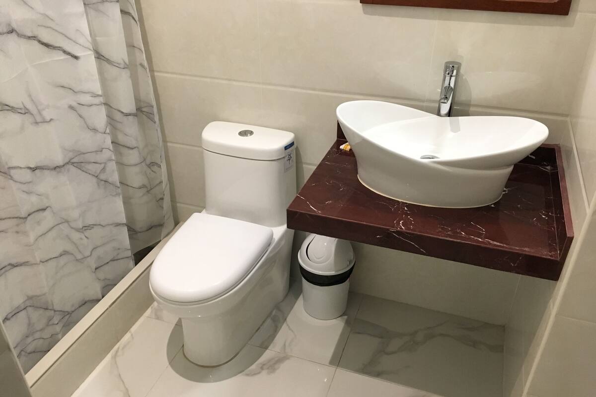 A bathroom with a toilet, sink, and marble flooring.