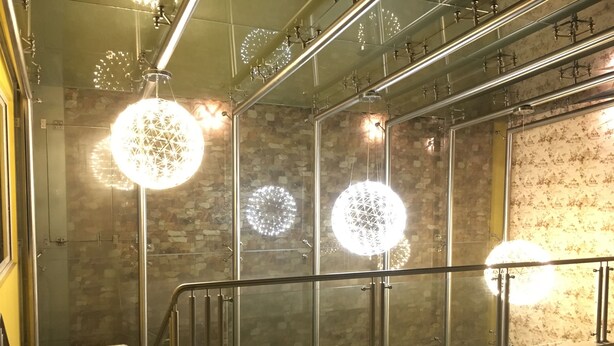 Un intérieur moderne avec une balustrade en verre, des luminaires sphériques décoratifs et un mur orné de motifs.
