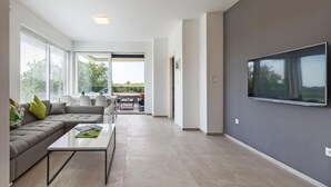 A modern living room with a grey sofa, a coffee table, and a flat-screen TV mounted on the wall. - Cozy apartment in Stinjan (Stinjan)