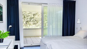 A bedroom with a bed, a bedside lamp, a potted plant, and a view of a balcony with a door leading outside. - Stunning apartment in Bergen aan Zee (Bergen aan Zee)