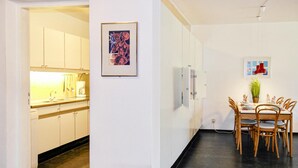A modern kitchen with white cabinets and a dining area with a wooden table and chairs. - Stunning apartment in Bergen aan Zee (Bergen aan Zee)