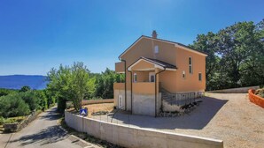 A two-story house with a balcony, a driveway, and a view of the landscape. - Amazing home in Risika (Risika)