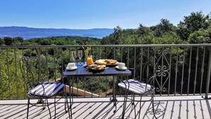 A balcony with a table set for breakfast, overlooking a scenic landscape. - Amazing home in Risika (Risika)
