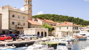 Un puerto deportivo con barcos amarrados, una iglesia con campanario y edificios con techos de tejas rojas.