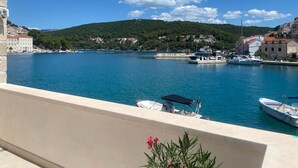 Un puerto deportivo con barcos amarrados, un mar azul cristalino y un paisaje montañoso al fondo.