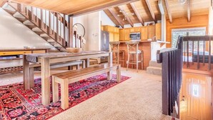Une cuisine moderne avec des poutres en bois, un coin repas avec un banc et un escalier.