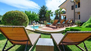 Un área junto a la piscina con sillones de mimbre.