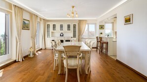 Un comedor amplio con una mesa y sillas de madera, una cocina con armarios blancos y un balcón con cortinas.