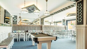 Ein Billardtisch in einem Raum mit weißen Stühlen und einem blauen Teppich.