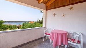 A balcony with a view of the sea, two white chairs, a table with a checkered tablecloth, and decorative starfish on the wall. - Beach front home in Barbat na Rabu (Barbat na Rabu)